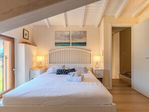 A bedroom with a bed, two bedside tables, a window, and a door. - La Terza Casa by Interhome (Tremezzina)