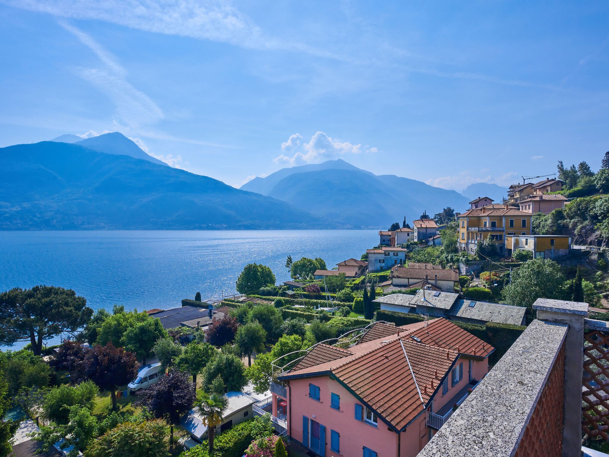 Un pueblo a orillas de un lago con arquitectura tradicional, jardines en terrazas y una vista despejada del lago y las montañas.
