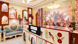 Un hall d’hôtel de charme, avec des meubles richement décorés, des œuvres d’art et un panneau indiquant qu’il propose un service de navettes pour les entreprises.