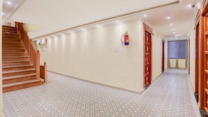 Un couloir doté d’un revêtement de sol à motifs, d’un escalier en bois et d’un extincteur fixé au mur.