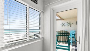 Ein Zimmer mit Blick auf den Strand, eine Tür, die nach draußen führt, und ein Stuhl daneben.