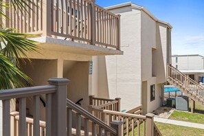 A residential building with a balcony, a staircase, and a pool area. - 2BR Pet Friendly Beach View Pool Sleeps 7 Condo! (Panama City Beach)