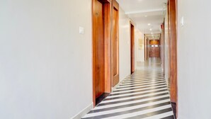 A long, narrow hallway with wooden doors and a striped floor. - Palette Patel Nagar (Bhopal)