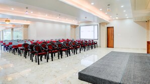 A conference room with rows of chairs, a projector screen, and a podium. - Palette Patel Nagar (Bhopal)