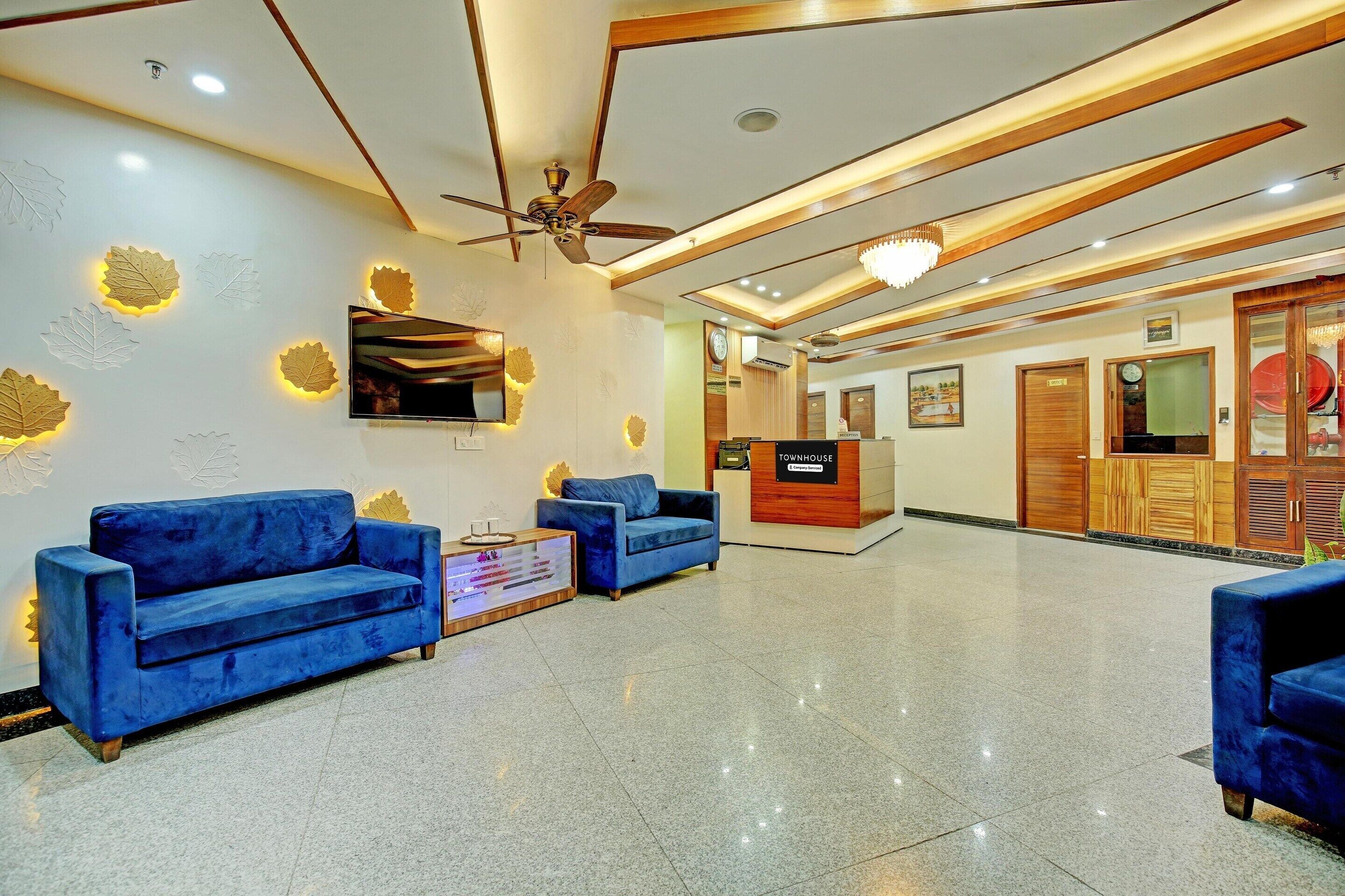 A reception area with a reception desk, two blue sofas, a ceiling fan, and a clock on the wall.