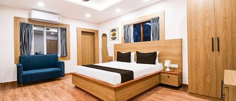 A modern bedroom with a wooden bed, a blue sofa, and a ceiling fan.