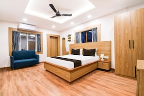A bedroom with a bed, a ceiling fan, a sofa, a wardrobe, and a window with curtains.