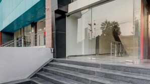 A modern building with a glass facade, a set of stairs leading to a door, and a metal railing. - Deluxehotel Virat Inn (Gorakhpur)