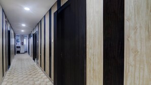 A hallway with a patterned floor, doors, and a ceiling with recessed lighting. - Deluxehotel Virat Inn (Gorakhpur)