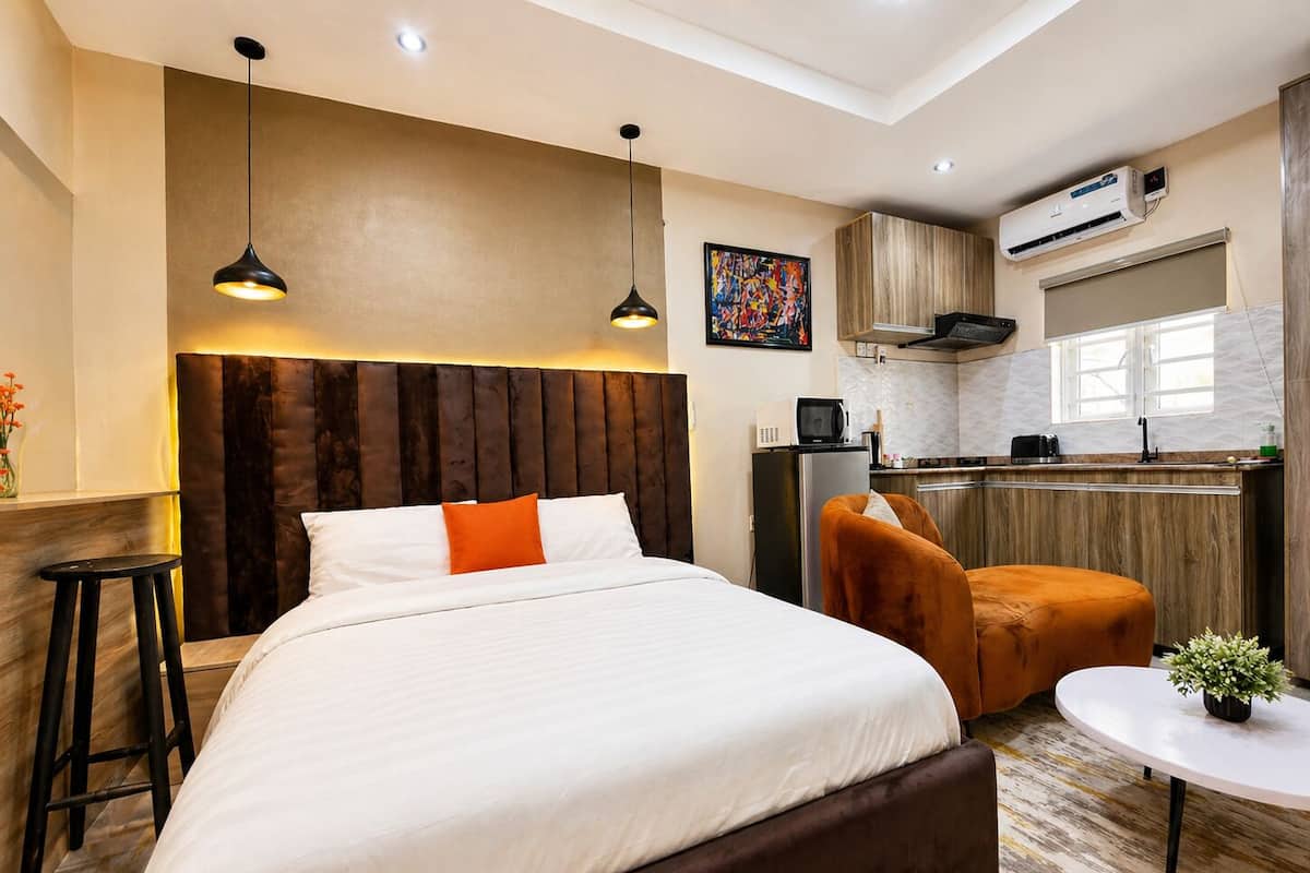 Quarto de hotel moderno com uma cama grande, pequena área de cozinha e mesa de jantar.