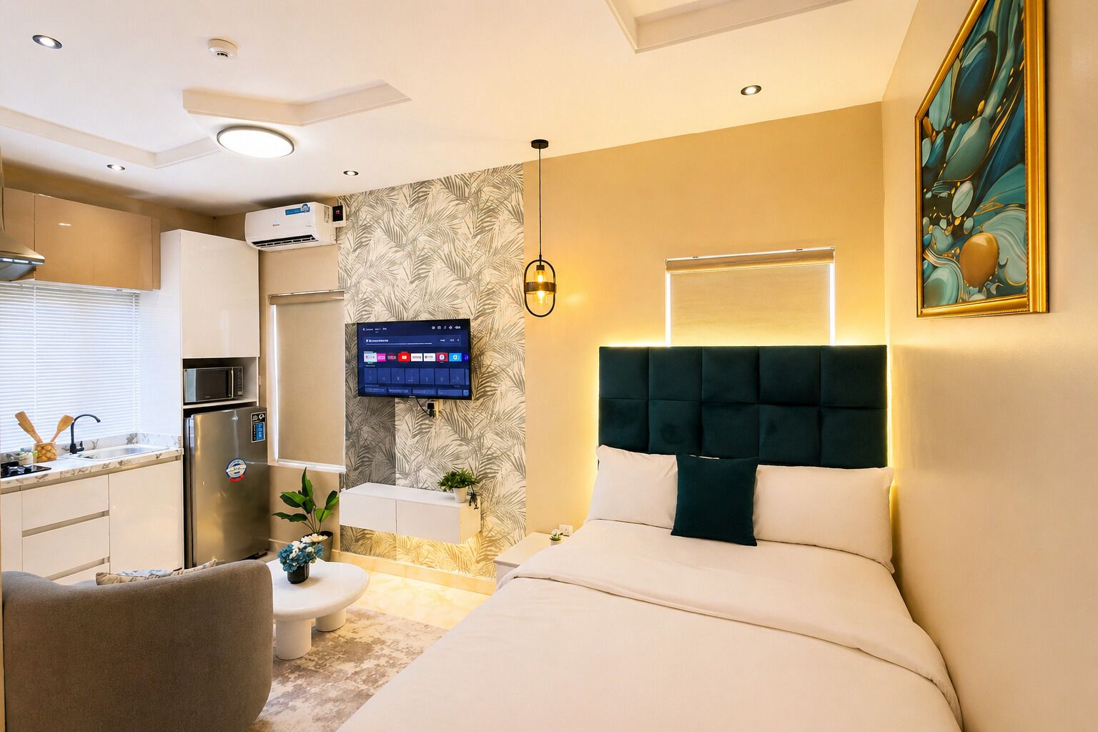 A modern hotel room with a bed, a desk, a TV, and a kitchenette.
