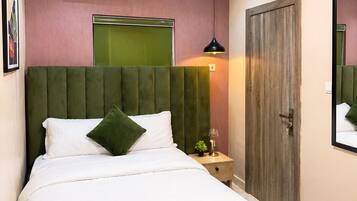Quarto com cama, mesa de cabeceira, luminária, ar-condicionado e porta.