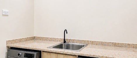 A laundry room with two front-loading washing machines, a sink, and a countertop.