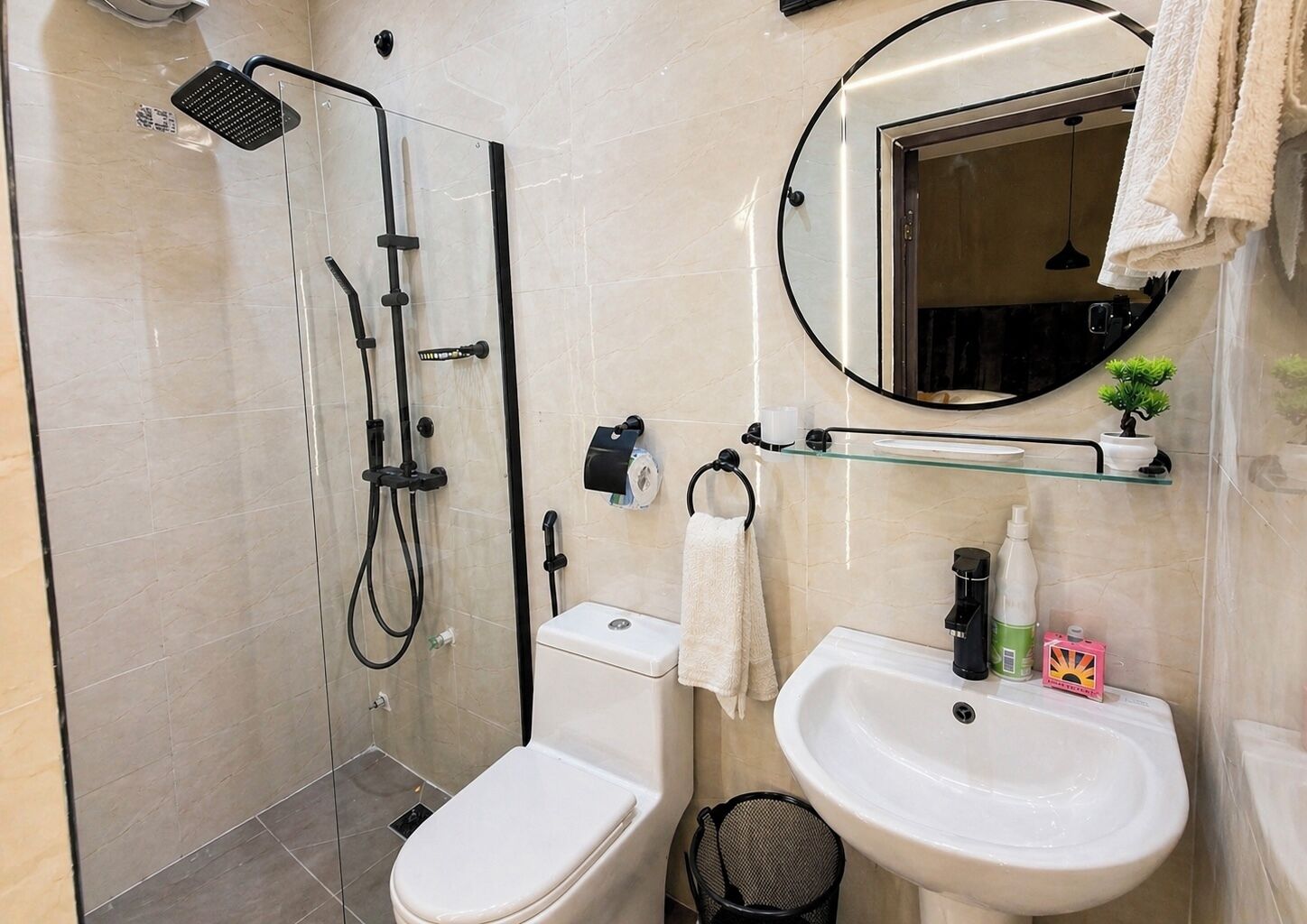 A bathroom with a glass-enclosed shower, a toilet, a sink, and a mirror.