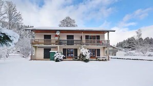 Un bâtiment à deux étages doté d’un balcon, d’une terrasse couverte et surplombant un paysage enneigé.
