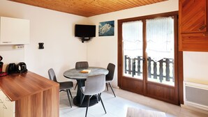 Un espace repas comprenant une table ronde, des chaises, un téléviseur fixé au mur et un plafond en bois.