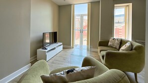 Ein modernes Wohnzimmer mit Flachbildfernseher, einer Couch und einem Glastisch.