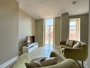 Ein modernes Wohnzimmer mit Flachbildfernseher, einer Couch und einem Glastisch.
