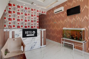 A hotel reception desk with a 'HOTELO' sign, a fish tank, and a modern interior design.