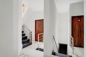 Un escalier avec une rampe, une porte en bois et un portail en métal.