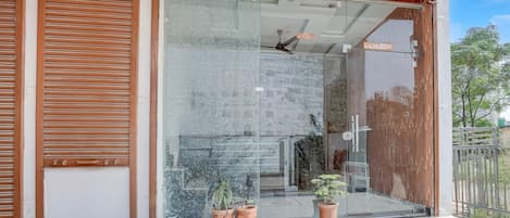 Un edificio moderno con entrada de vidrio, contraventanas de madera y plantas en macetas.