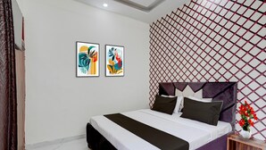 A modern hotel room with a bed, a nightstand, a decorative wall panel, and two framed artworks. - Saver Single Hotel O Isbt Mohali Holiday (Mohali)