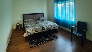 A bedroom with a bed, a ceiling fan, a chair, and a window with curtains. - 4-bedroom house in delightful Coimbatore with cool AC and space (Coimbatore)
