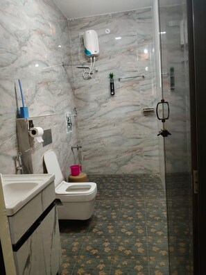 Un baño con inodoro, lavabo y zona de ducha.