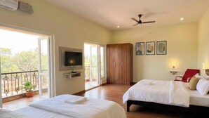 A hotel room with two beds, a TV, a balcony, and a ceiling fan. - 4-bedroom house in delightful Coimbatore with cool AC and space (Coimbatore)