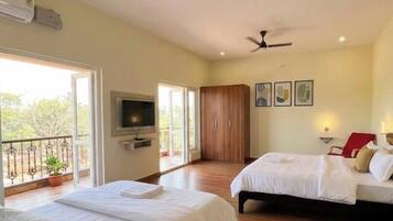 Une chambre d’hôtel avec deux lits, une télévision, un balcon et un ventilateur de plafond.