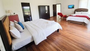 A hotel room with two beds, a TV, a ceiling fan, and a wooden floor. - 4-bedroom house in delightful Coimbatore with cool AC and space (Coimbatore)