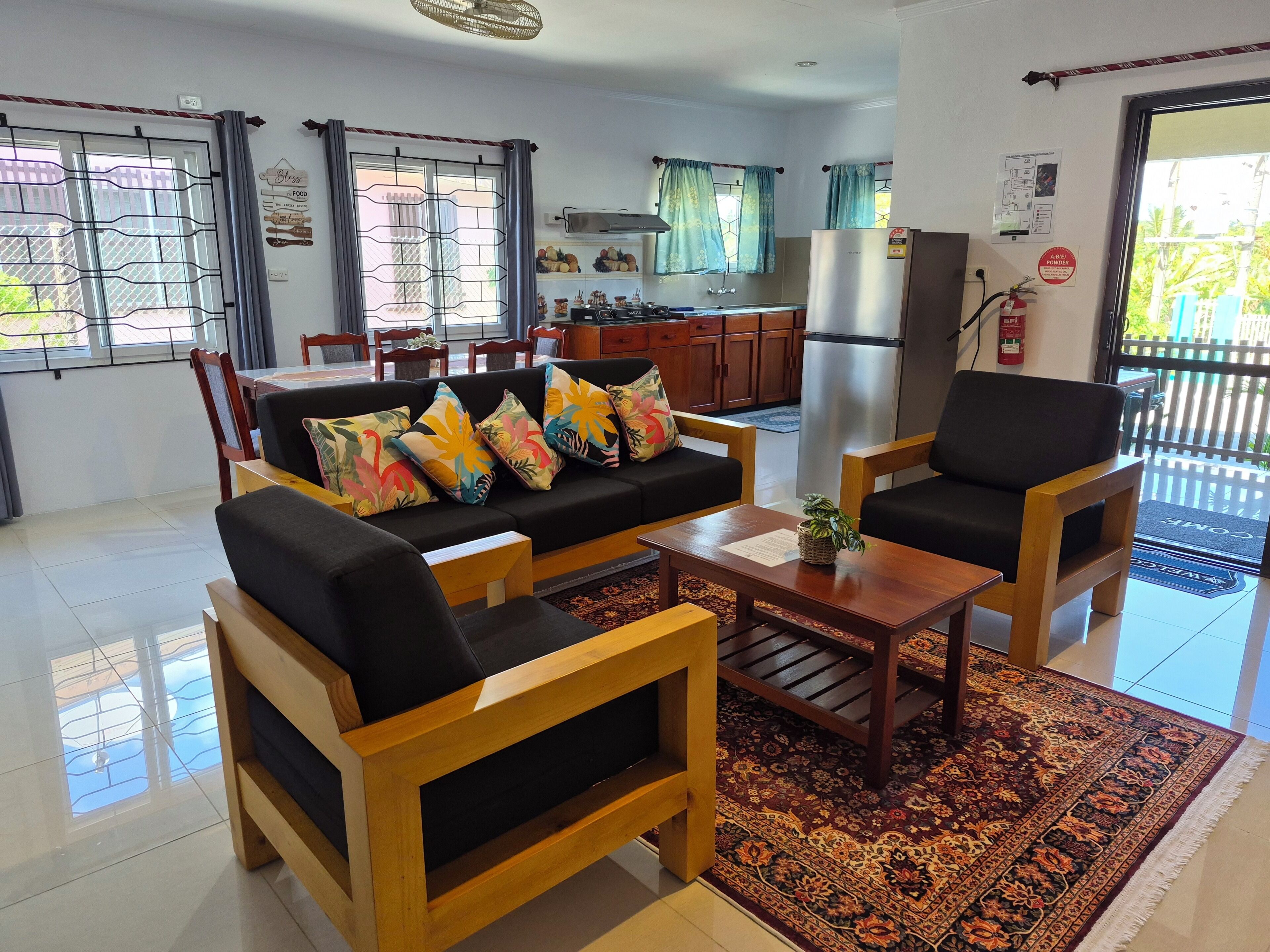 Una sala de estar con sofá, sillones, una mesa de centro y un tapete estampado.