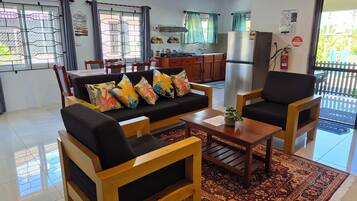 Una sala de estar con sofá, sillones, una mesa de centro y un tapete estampado.