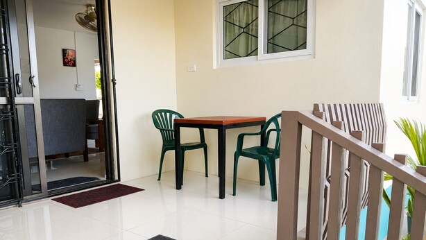 Entrada de hotel con un felpudo que dice 'BIENVENIDOS', una mesa con sillas y una escalera.
