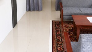Una sala de estar con un sofá, una mesa de centro, un televisor y una alfombra estampada.