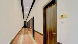 A hotel hallway with a number sign '101' on the wall, doors, and a tiled floor.