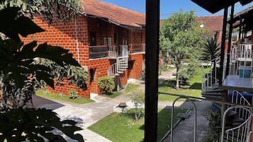 Um edifício de tijolos com telhado de telhas vermelhas, uma escadaria e uma pequena área de jardim com plantas e um caminho.