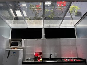 A kitchen with a microwave, sink, and stove, a skylight, and a view of trees.