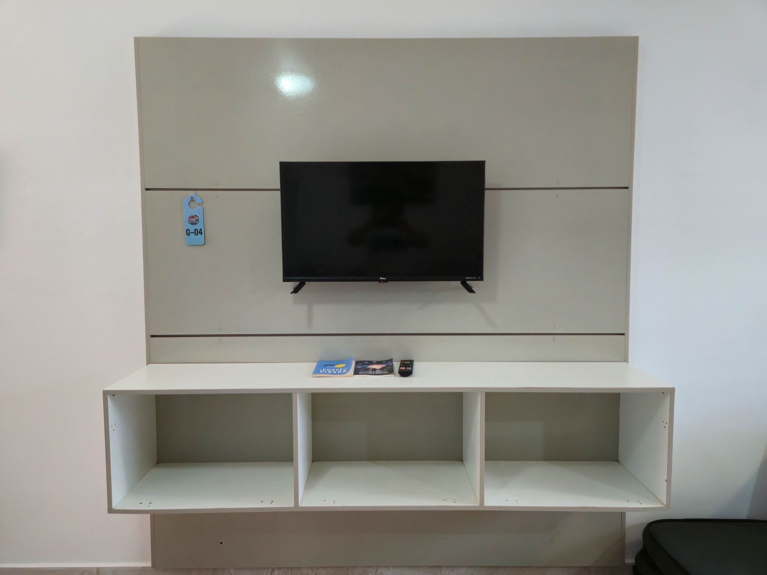 Ein Flachbildfernseher an der Wand, darunter eine weiße Unterhaltungseinheit.