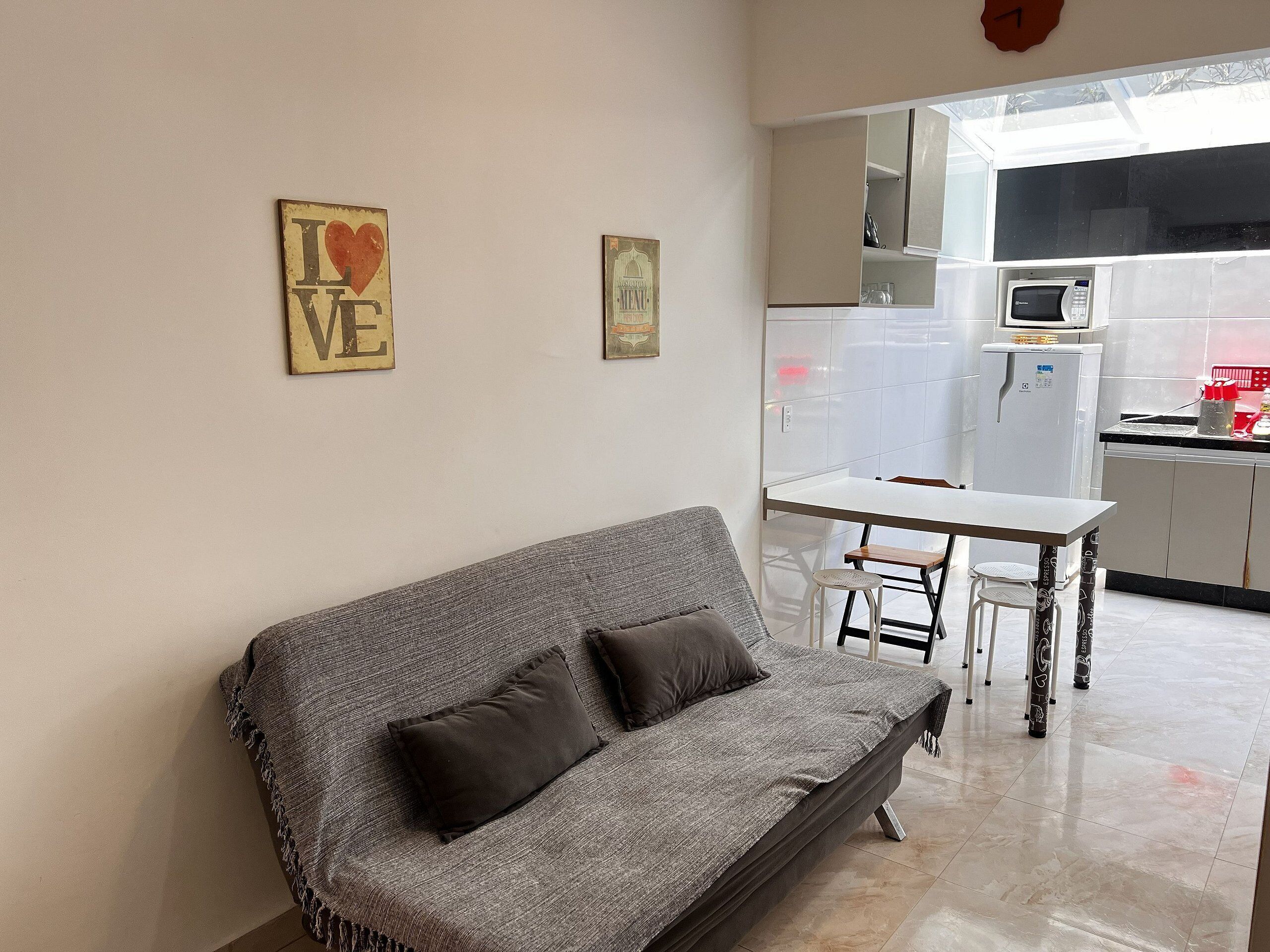 Un espace de vie comprenant un canapé, une petite table et une cuisine à l’arrière-plan.
