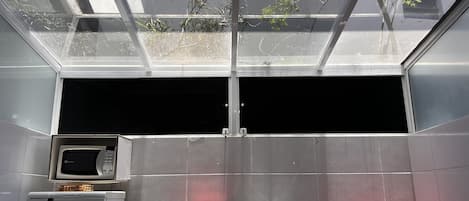 Una cocina con microondas, fregadero y estufa, un tragaluz y vistas a árboles.