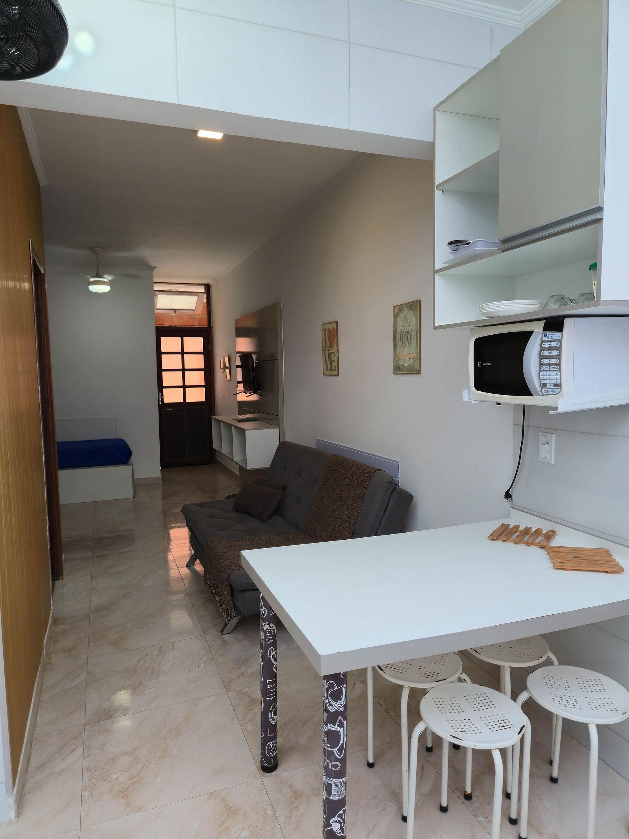 Un espace de vie compact comprenant un coin cuisine, un canapé, une table à manger et un petit téléviseur.