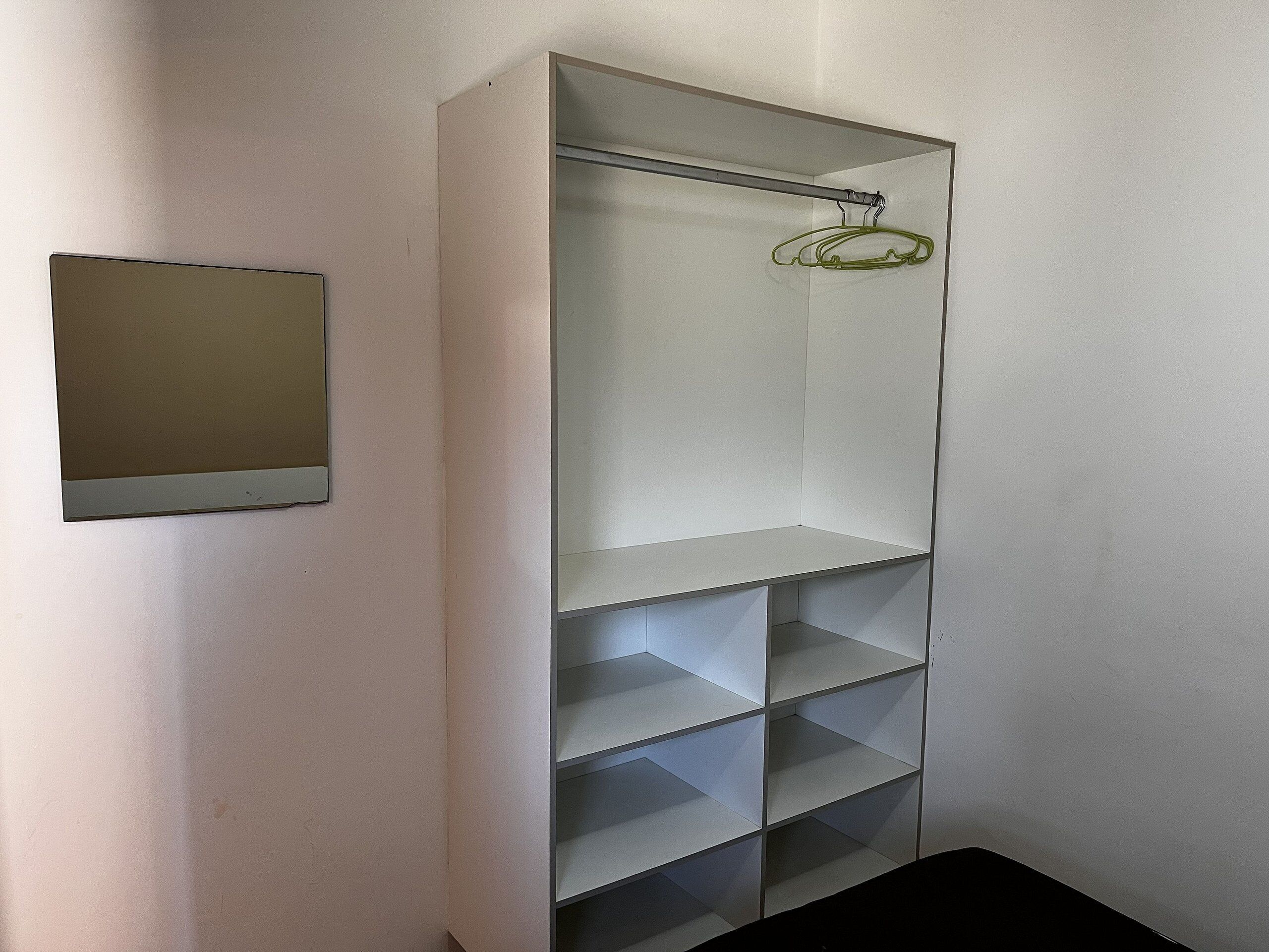 Un armario con varios estantes y una barra para colgar ropa.