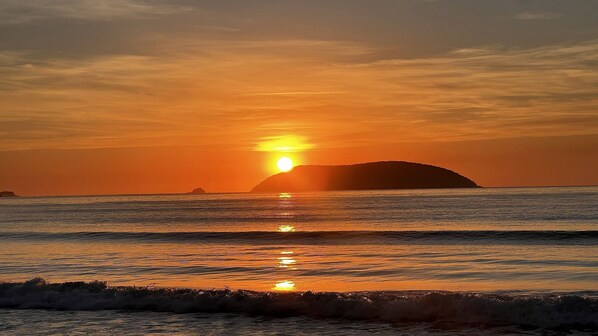A sunset over the ocean with a silhouette of an island.