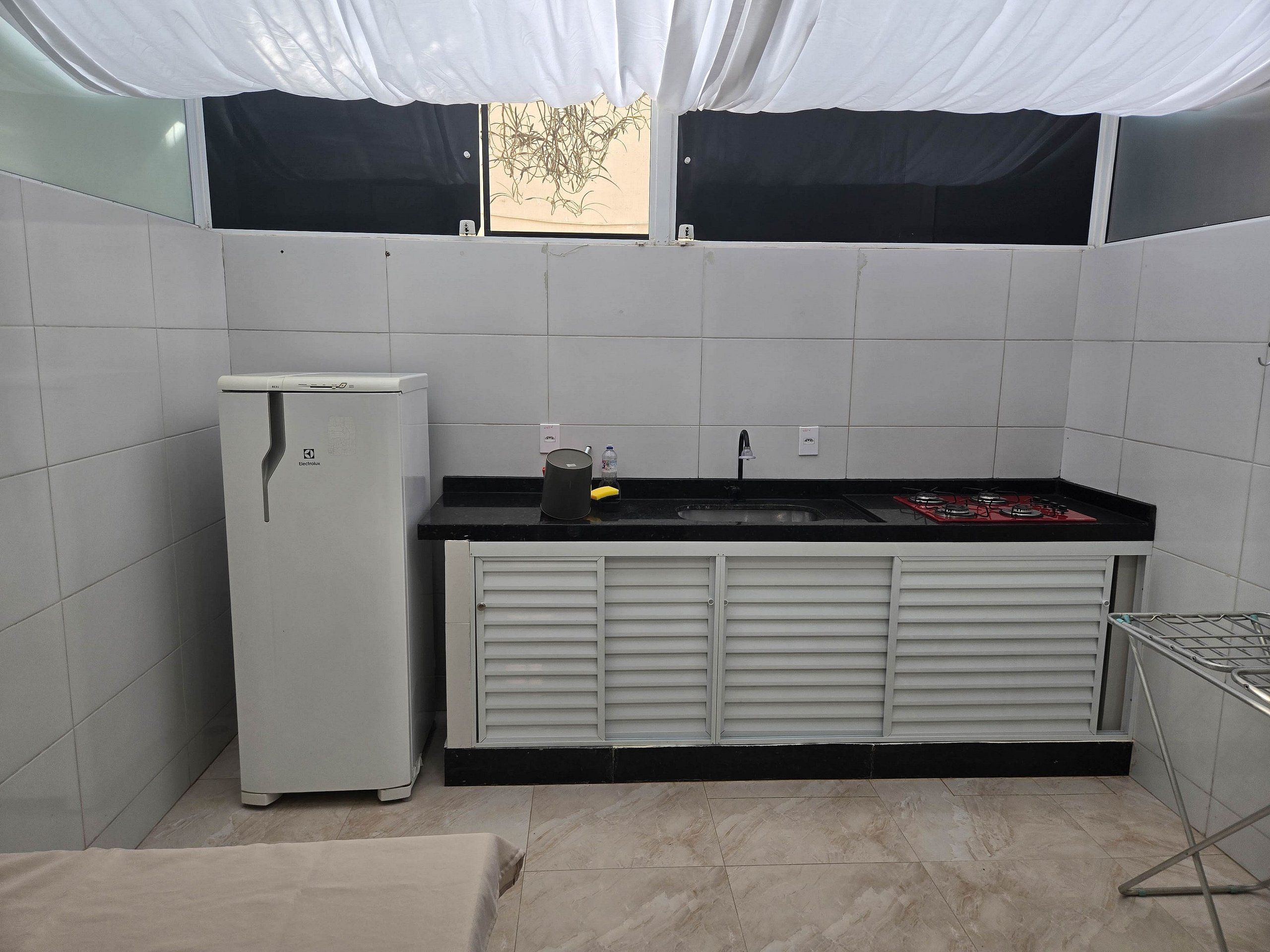 Uma cozinha compacta equipada com geladeira, pia e fogão.