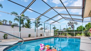 Una piscina coperta con tetto in vetro, circondata da palme e un recinto bianco.