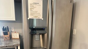 Et stålskab med vanddispenser, en seddel på døren og en køkkenbordplade med bestik.