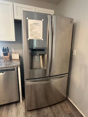 A stainless steel refrigerator with a water dispenser, a note on the door, and a kitchen counter with utensils. - Cozy family home minutes from Disney, fully equipped with Wi-Fi, pool… (Kissimmee)