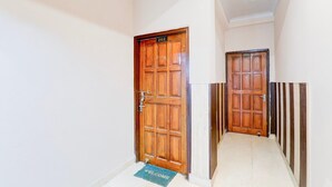 A hallway with wooden doors numbered 202 and 203, a welcome mat, and a tiled floor. - Saver Double Sharda Nagar Lucknow (Lucknow)