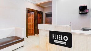 A hotel reception area with a reception desk, a waiting area with a bench, and wooden doors in the background. - Saver Double Sharda Nagar Lucknow (Lucknow)